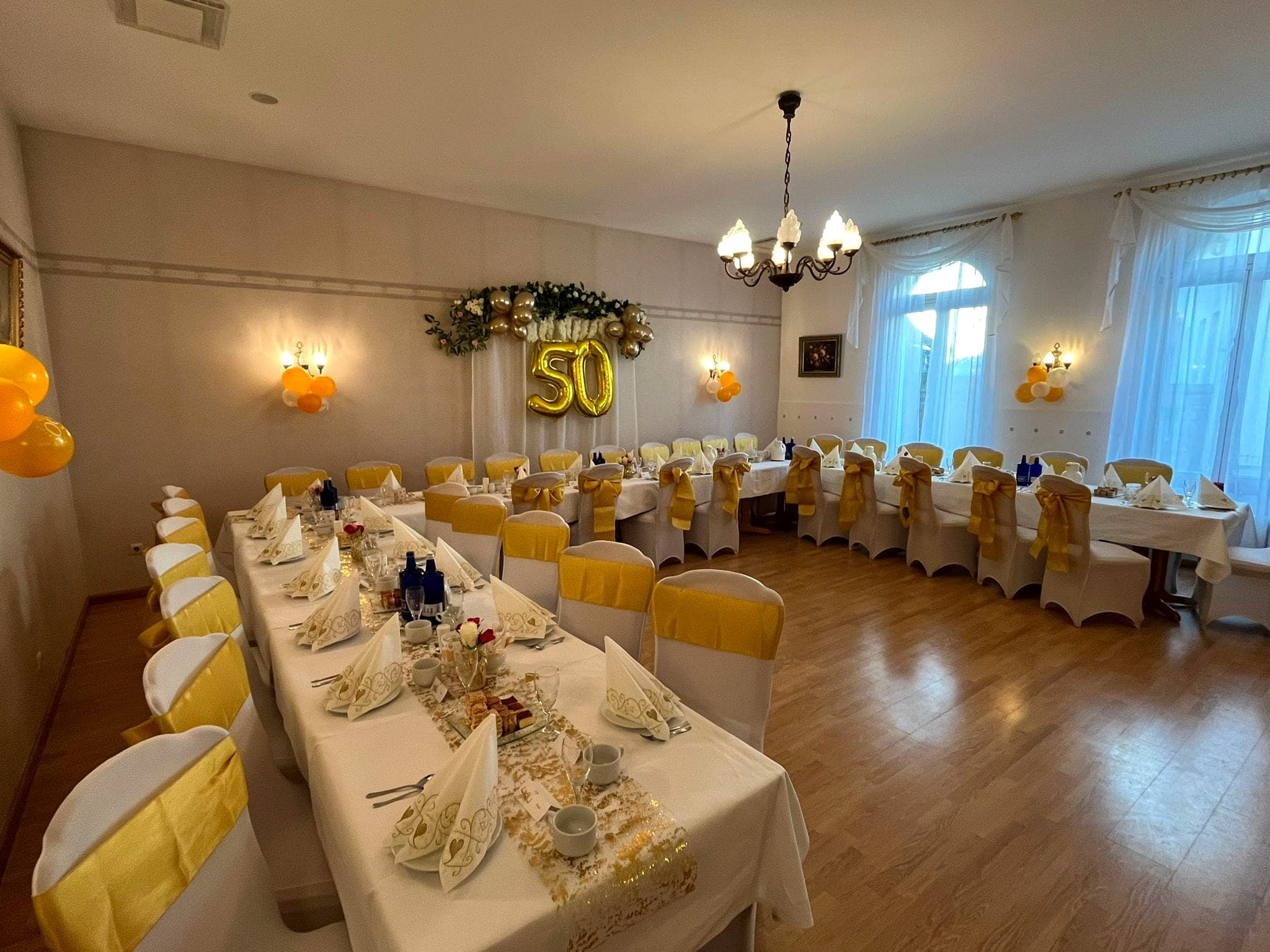 Bankettsaal, für eine Geburtstagsfeier mit langer Tafel und weiß bezogenen Stühlen eingedeckt